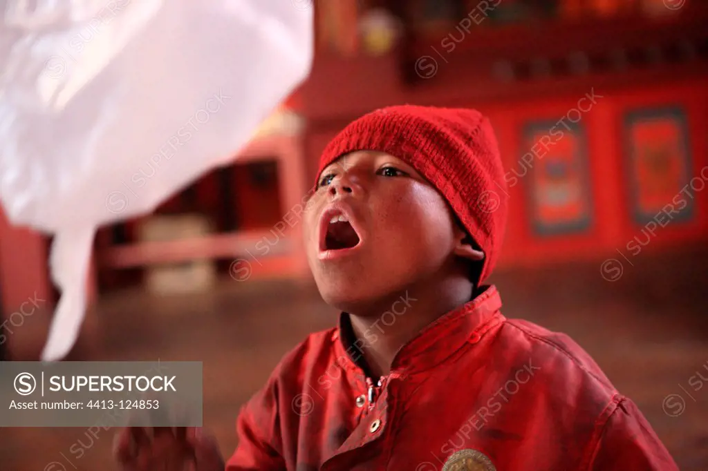 Young Buddhist monk playing with a packet Muktinath Nepal
