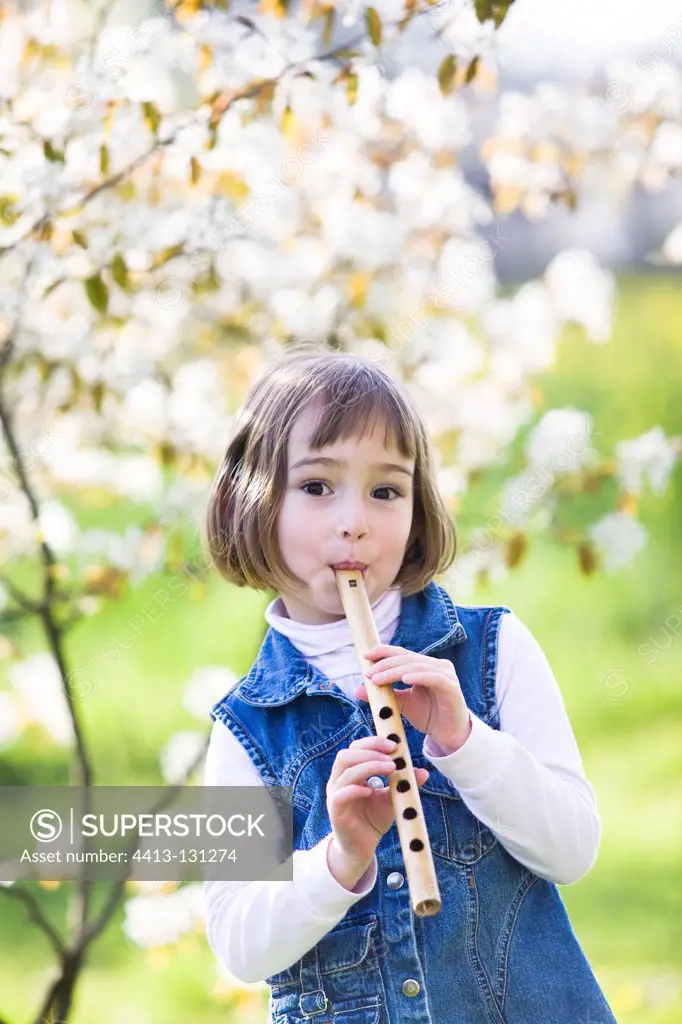 Little girl playing a flute carved from a reed