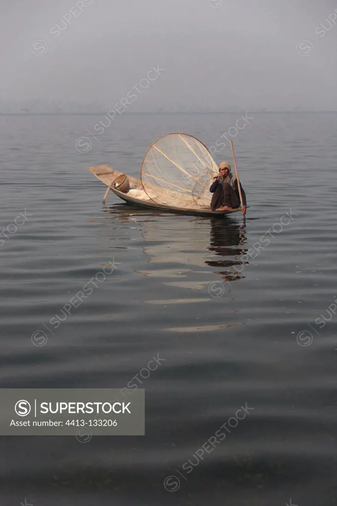 Man smoking on his fishing boat in the middle of Inle Lake