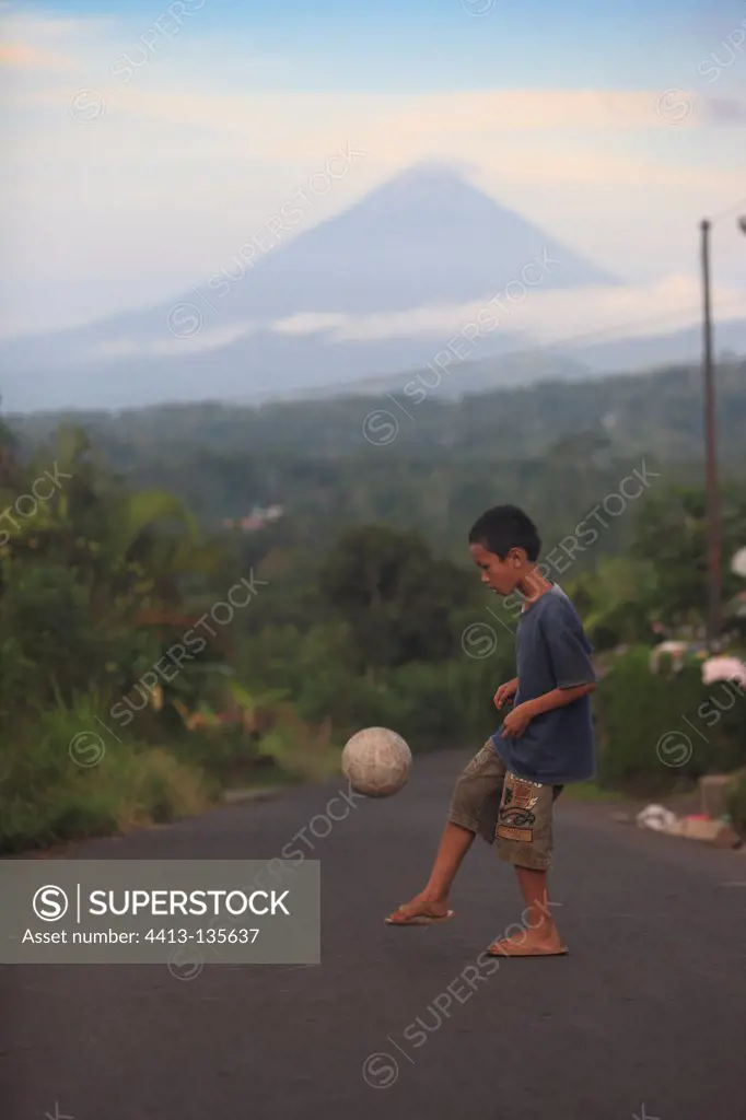 Boy playing ball and Abulobo volcano Bajawa Indonesia