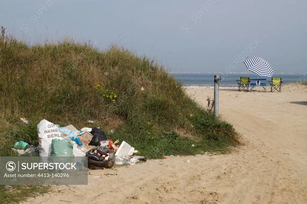 Table and chairs under a beach umbrella and garbage Normandy