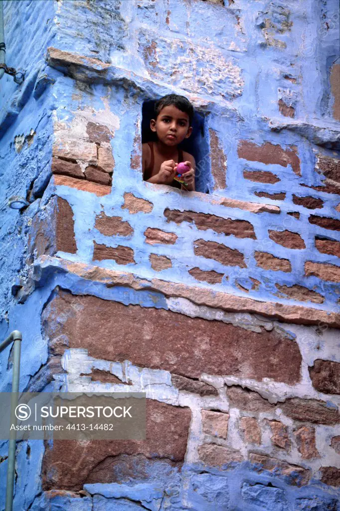 Child looking out of the window in a street of Jodhpur India
