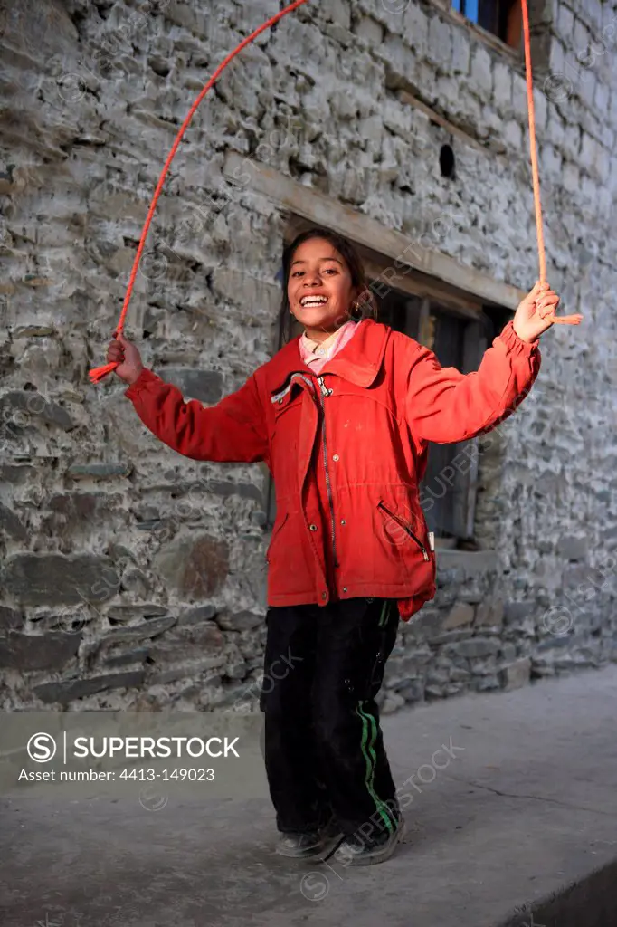 Girl playing jump rope outside a house India
