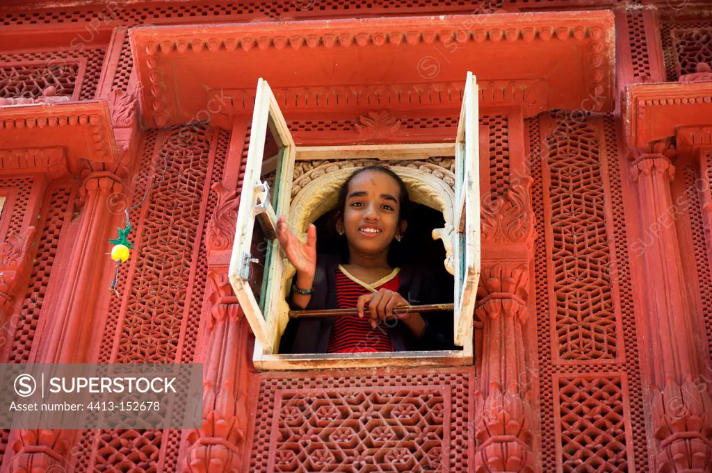 Girl looking out of window of mansion house Rajasthan India