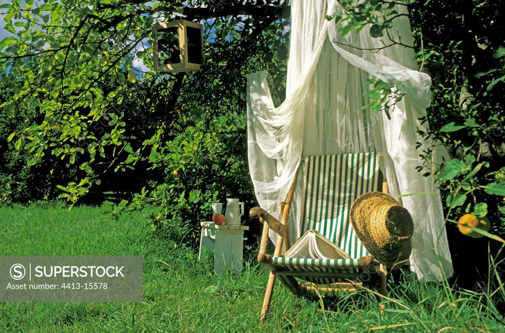 Long chair under a mosquito net in a private garden France