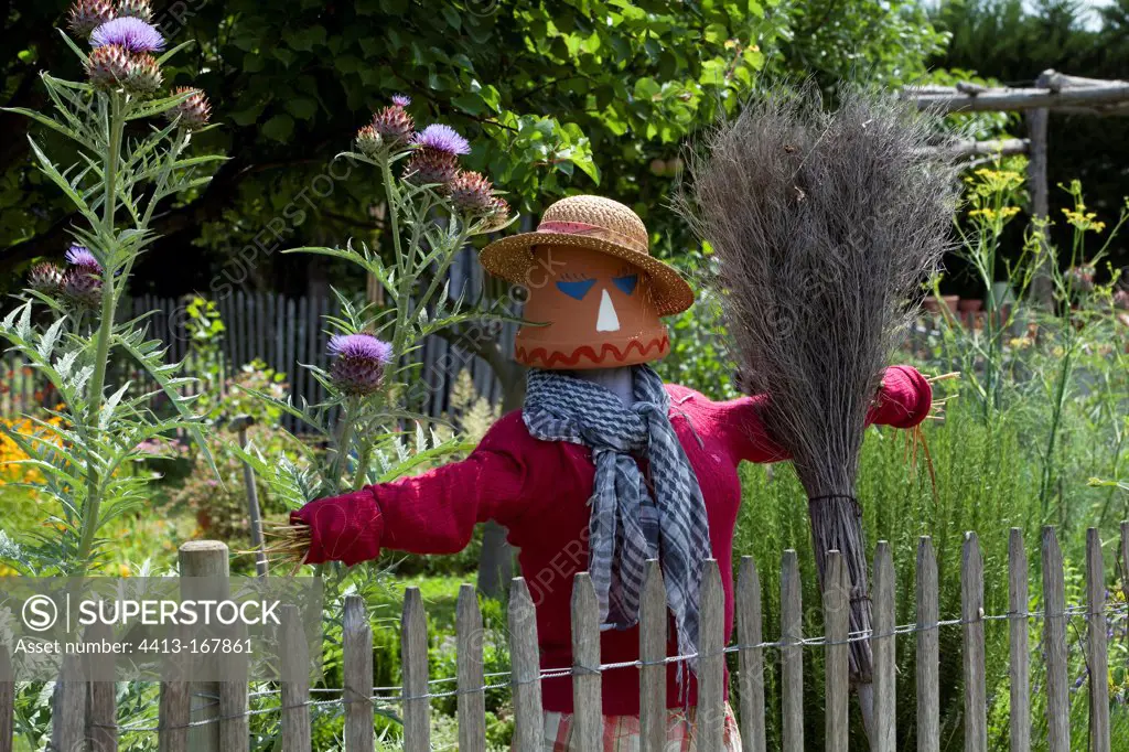 Scarecrow with a broom in a garden