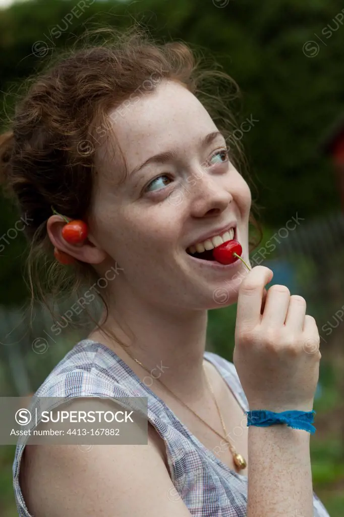 Young girl eating morellos cherries in a garden
