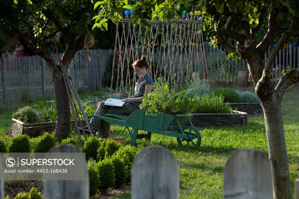 Young girl with wheelbarrow in an aromatic plants garden
