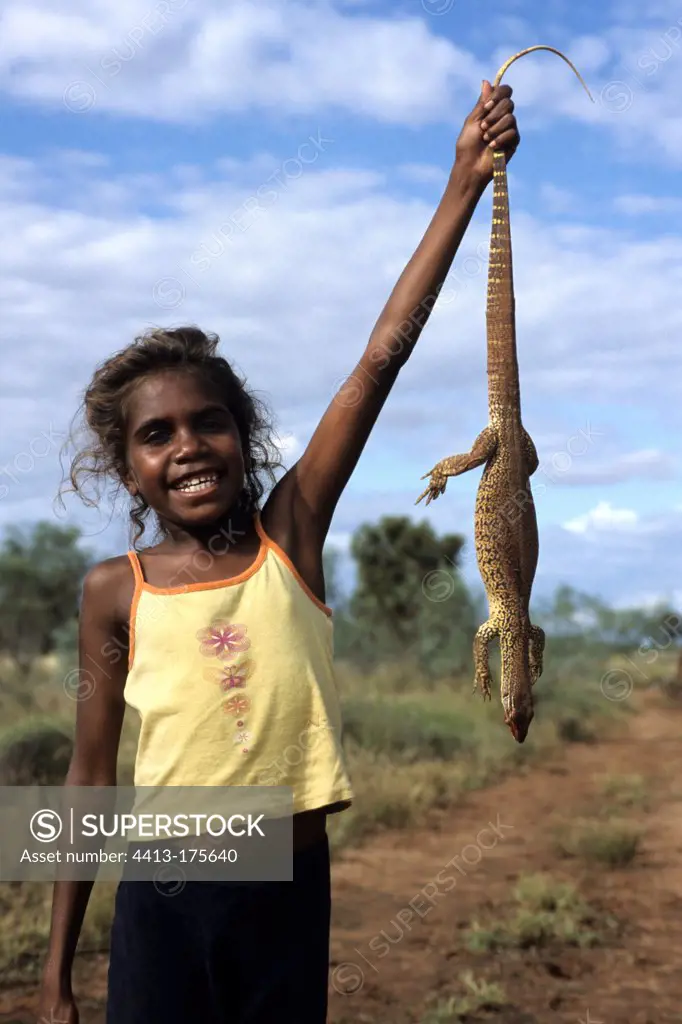 Aborginal girl holding an hunted sand monitor in Australia