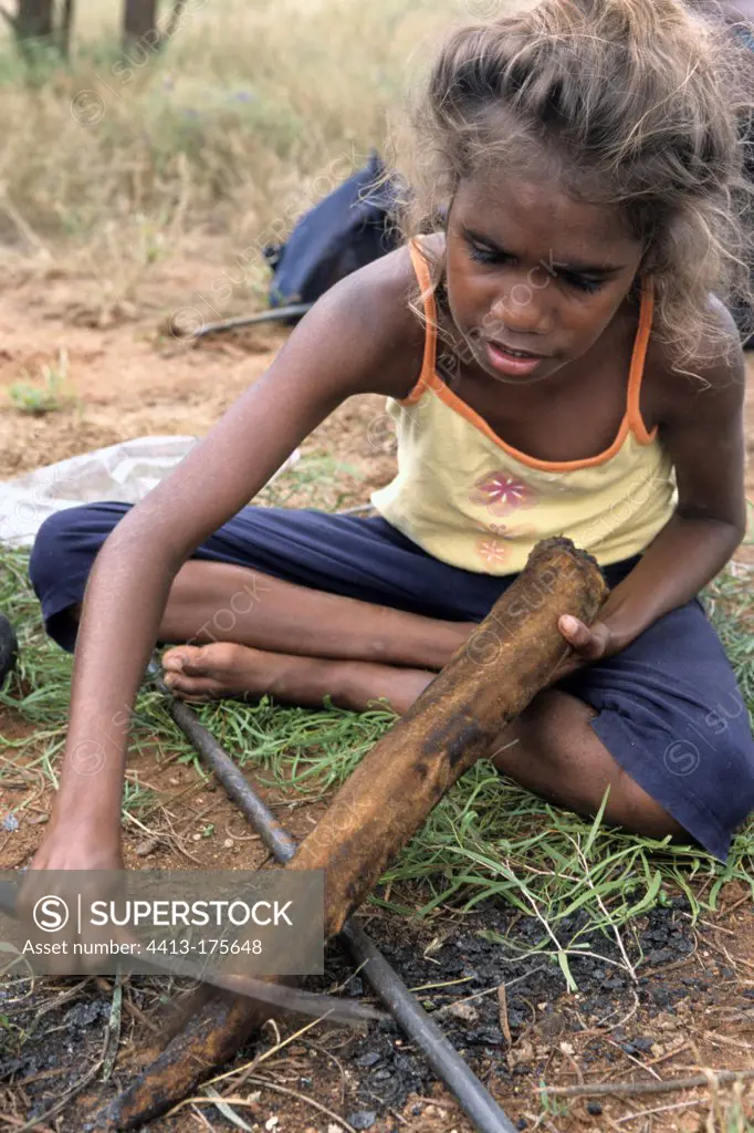Aboriginal girl cooking a kangaroo tail in Australia