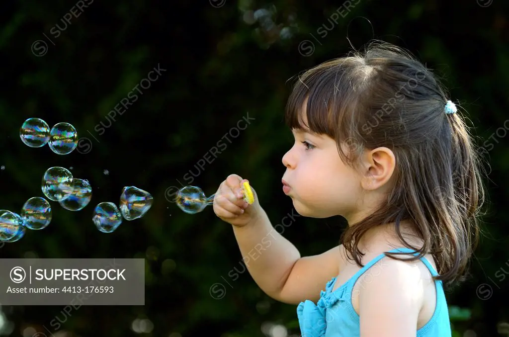 Girl making soap bubbles in a garden France