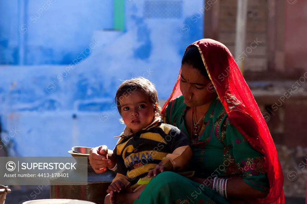 Indian woman with child sitting in front of Brahmin house