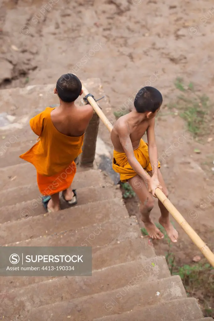 Child sliding down a banister bamboo Laos