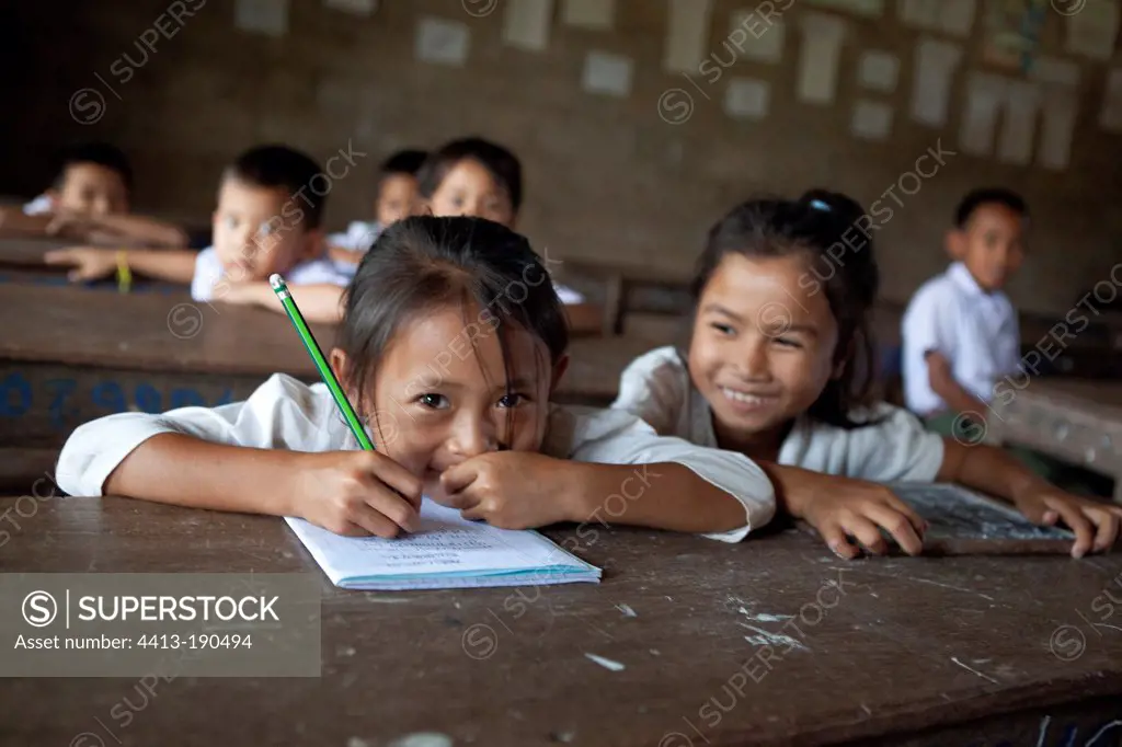 Girl smiling behind her desk in a school in Laos