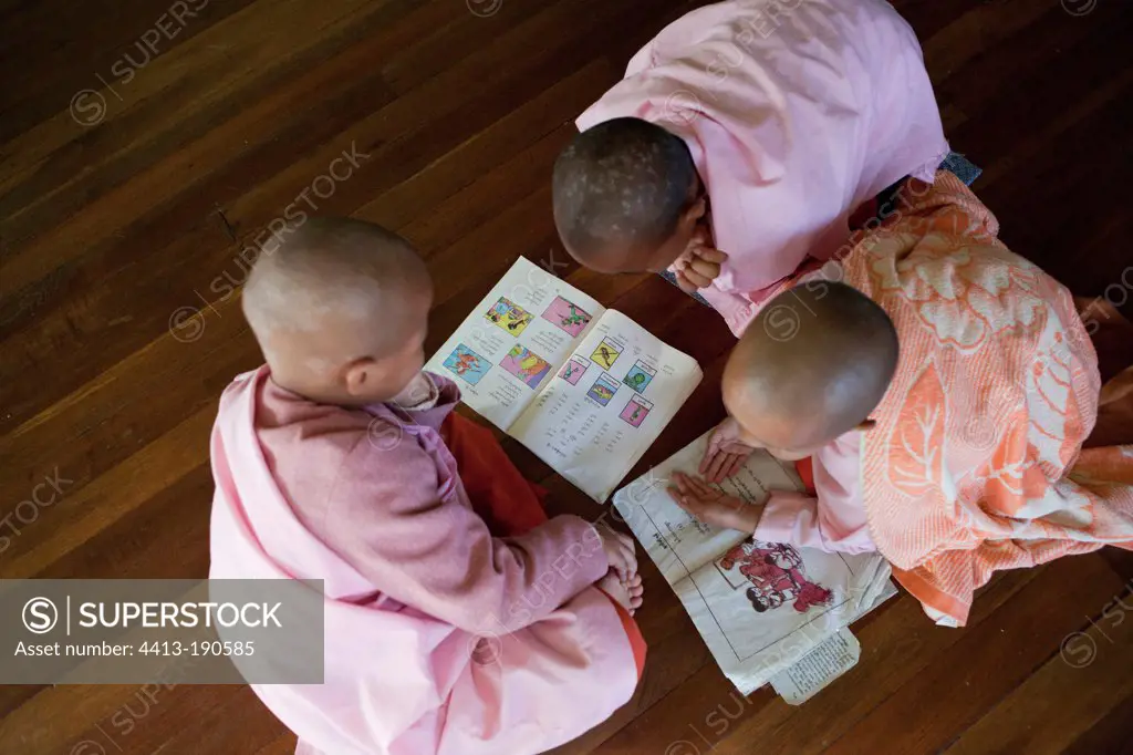 Young nuns learn to read a book in Burmese