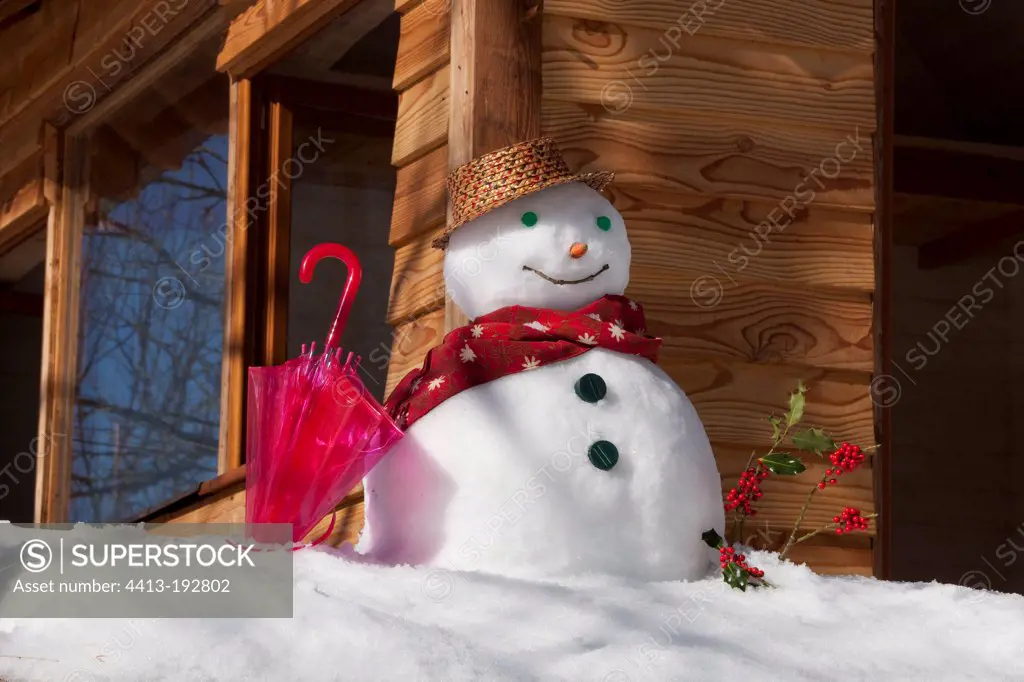 Snowman in front of a wooden chalet