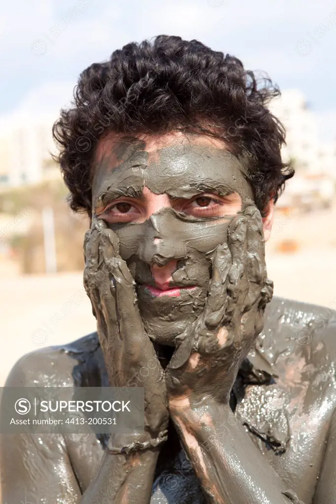 Tourist smearing mud on the banks of the Dead SeaJordan