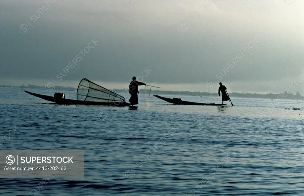 Fishermen on their boat at twilight Inle Lake Burma