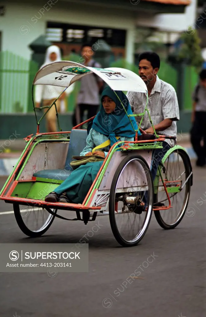 Girl transported by a rickshaw Java