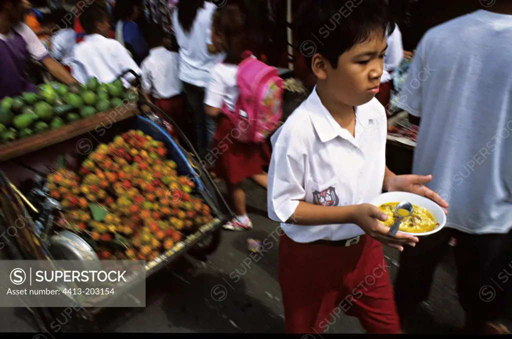 Schoolboy with his meals in a market Java