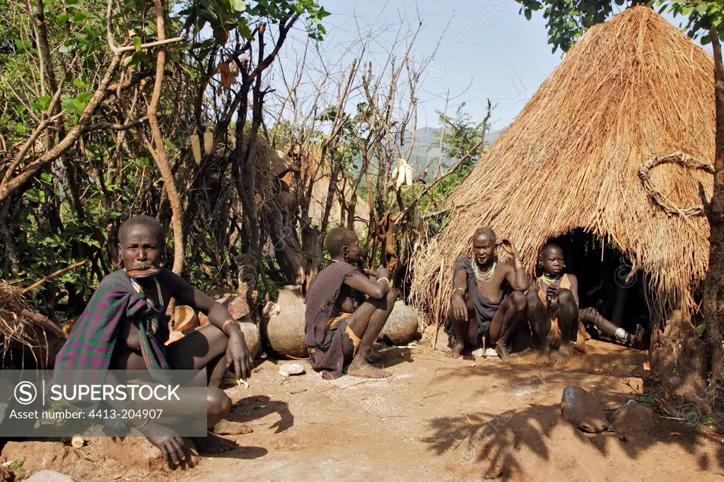 Surma women sitting in front of a straw hut Ethiopia