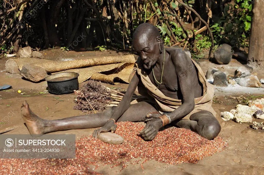 Surma old woman grinding corn Ethiopia
