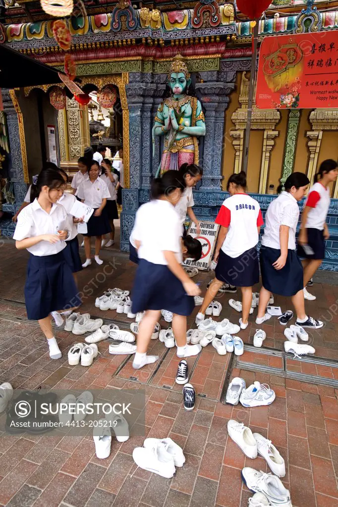 Young girls removing their shoes in front of a temple