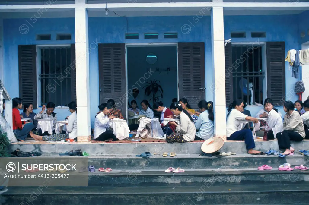 Women sitting in front of a house and embroidering Vietnam