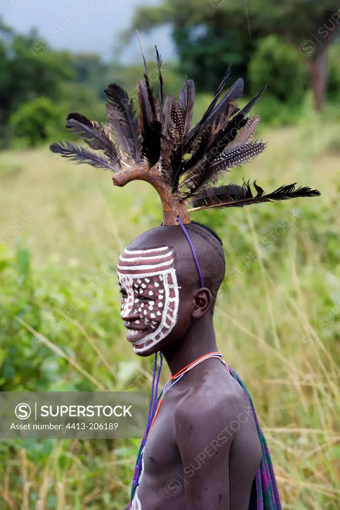 Body-painted Surma boy wearing a feather headdress