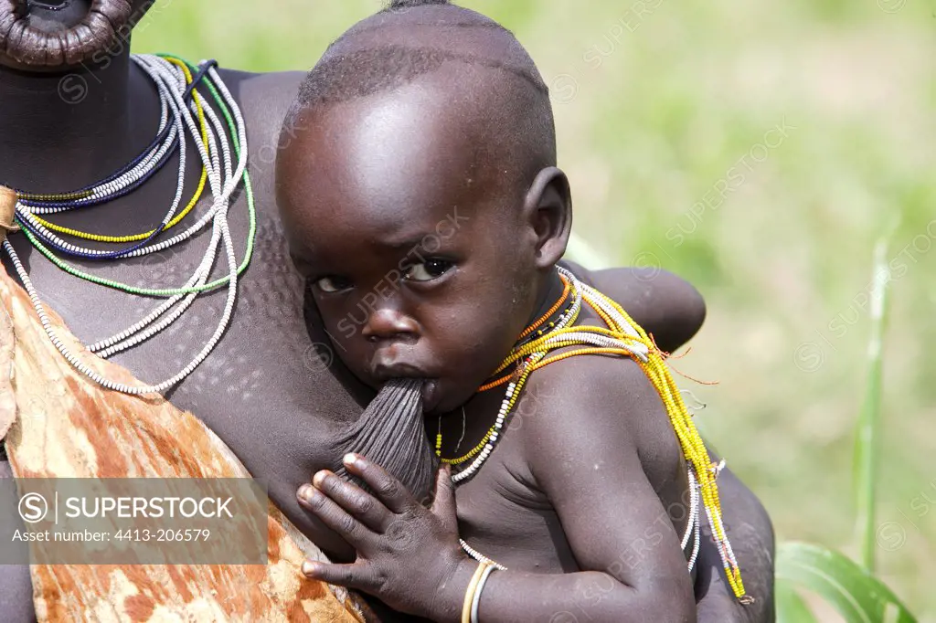 Portrait of a Surma infant sucking at mother's breast