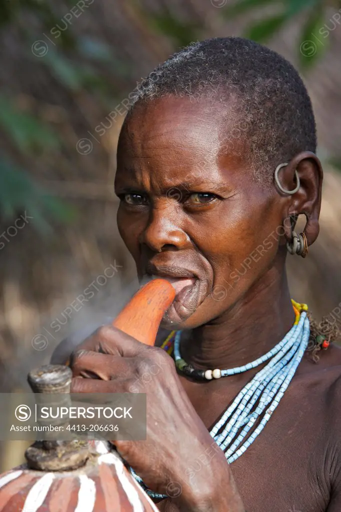 Portrait of a Surma woman smoking with a calabash Ethiopia