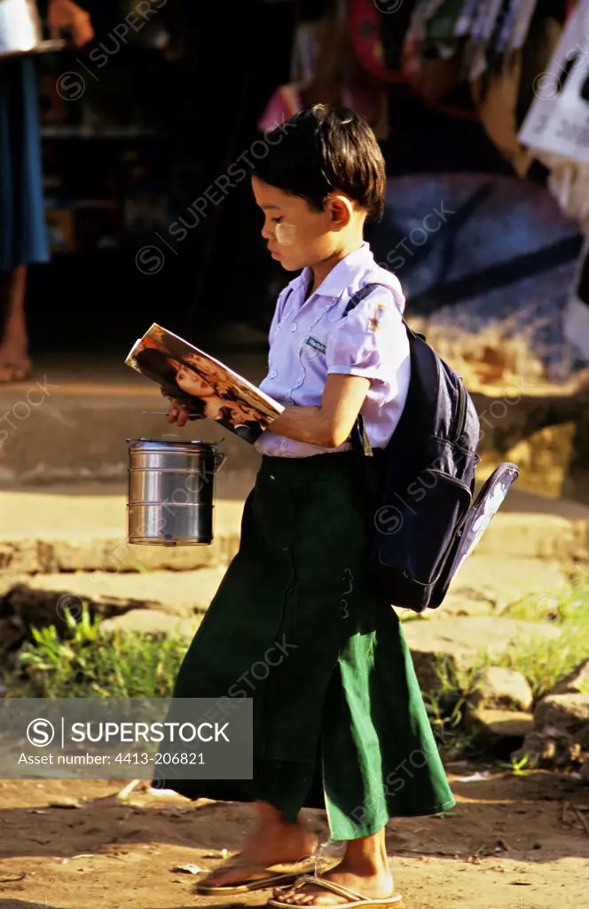 Little schoolgirl reading on the way to school Myanmar