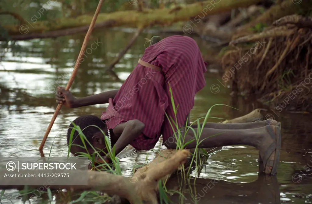Young Masai herdsman drinking water from Ruvu river Tanzania