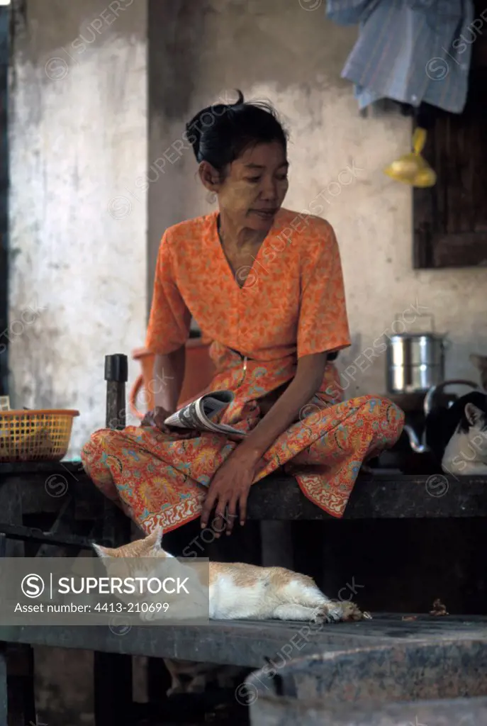 Thin woman sit on a table with cats Burma