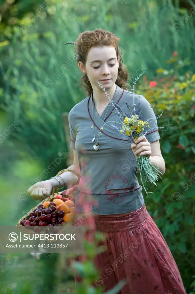 Teen girl holding a bouquet and a basket of fruits Provence