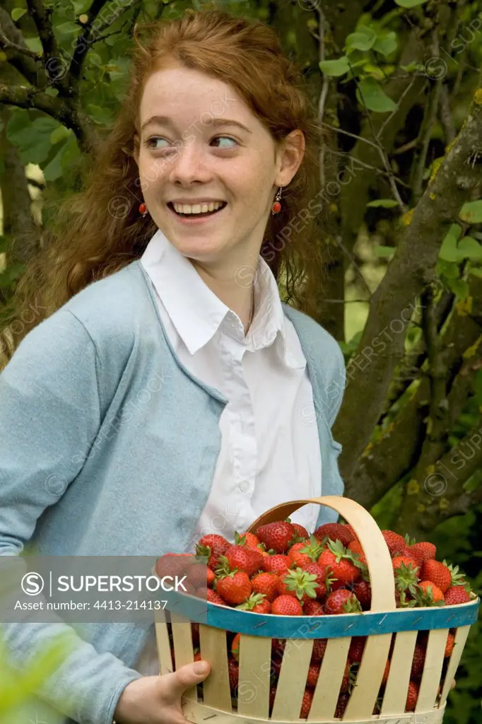 Portrait of a young girl with a basket of strawberries