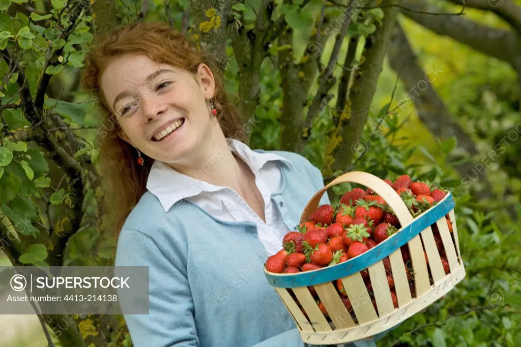 Portrait of a young girl with a basket of strawberries