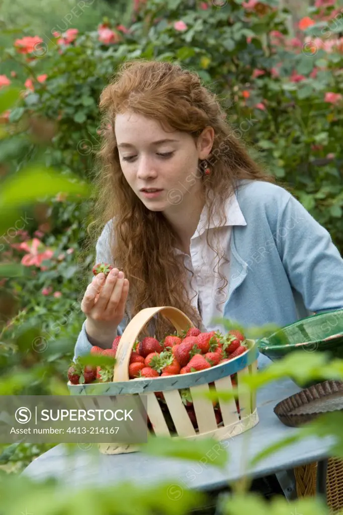 Young girl with a basket of strawberries in a garden