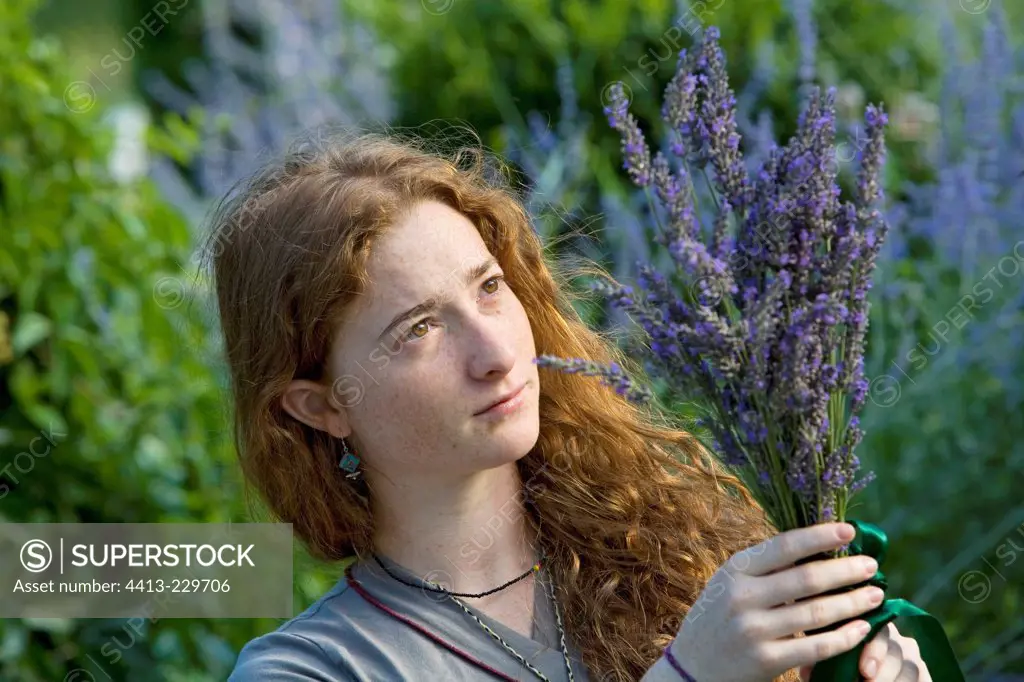 Young red-haired girl harvesting lavender in the garden