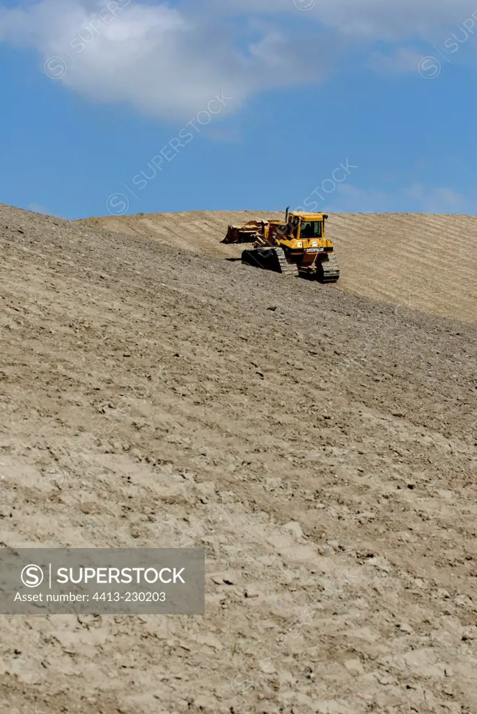 Bulldozer leveling a mine dump of a former potash mine