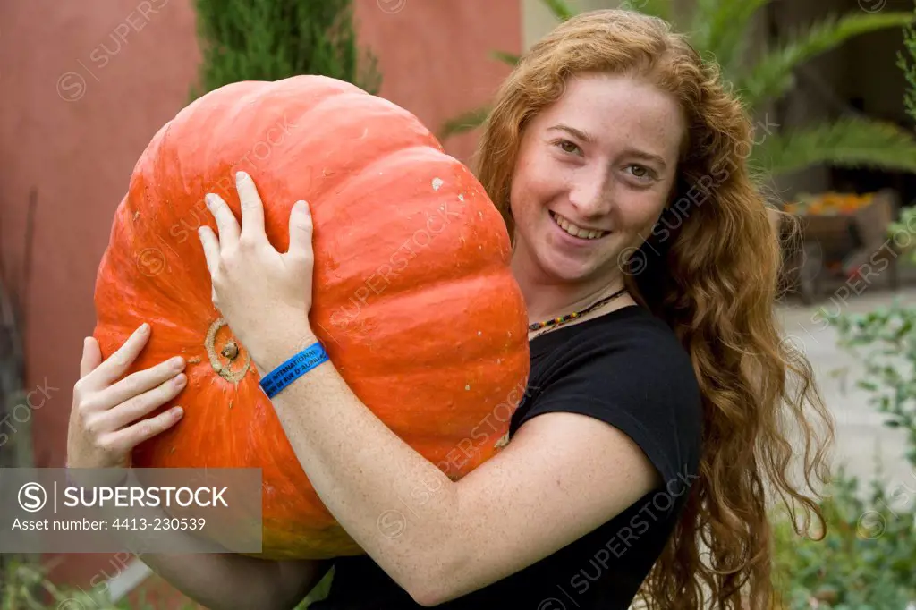 Young red-haired girl harvesting a squash 'Rouge d'Etampes'