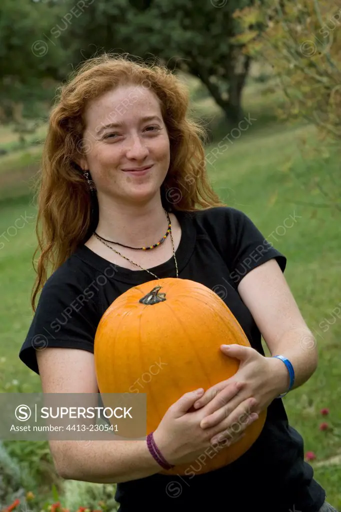 Young red-haired girl harvesting a squash 'Jack O'Lantern'