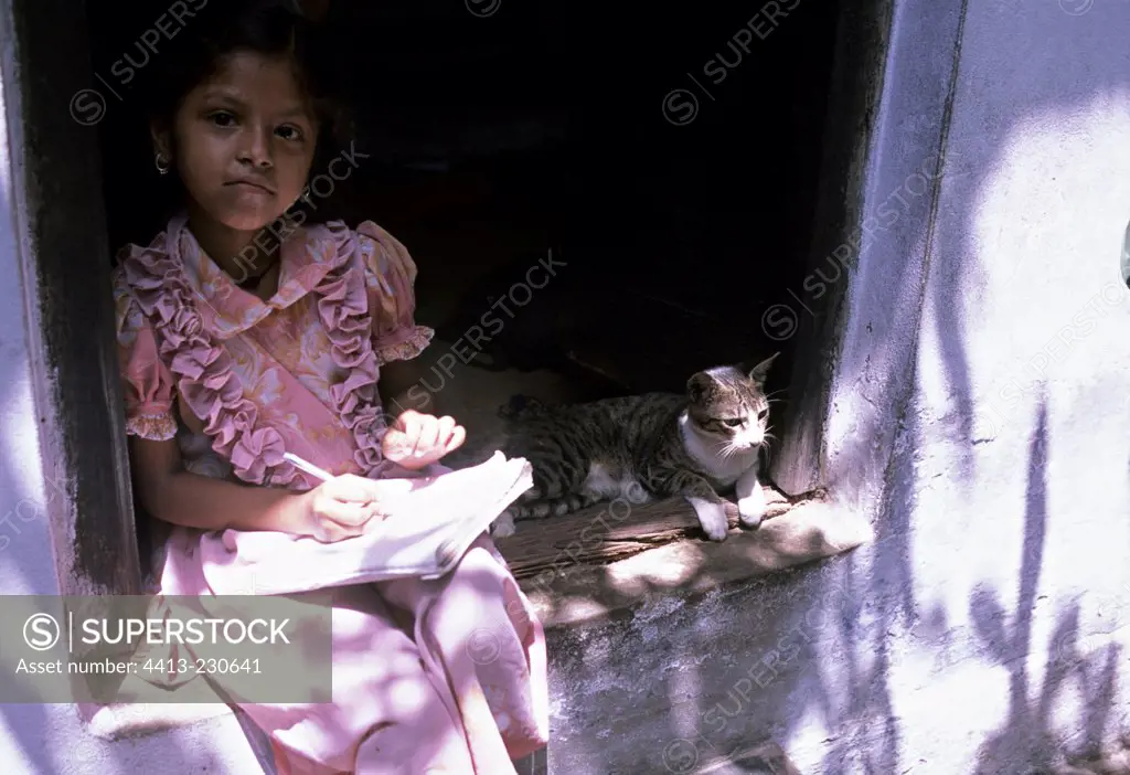 Girl writing on a copybook near a cat India