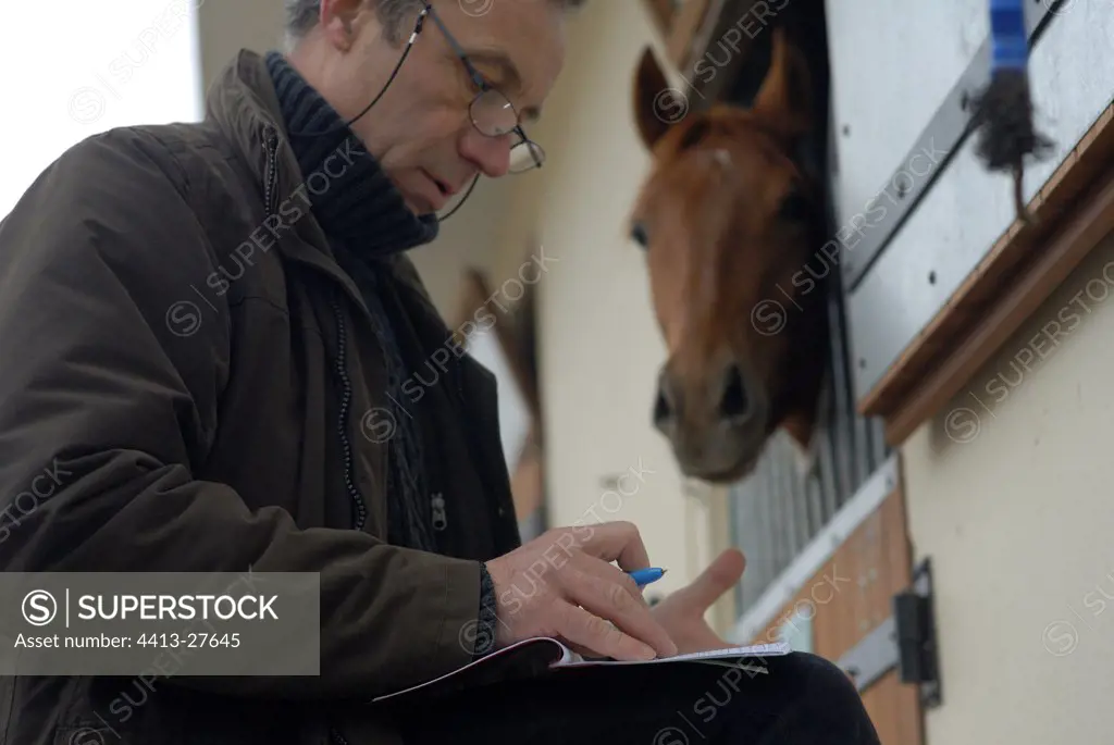 Equine veterinary surgeon filling a notebook with vaccination
