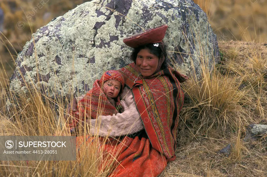 Woman in traditional clothe sitting with her child Peru