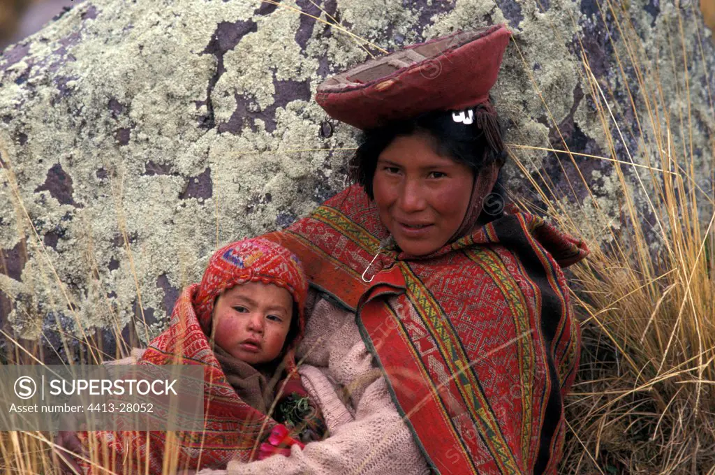Woman in traditional clothe sitting with her child Peru