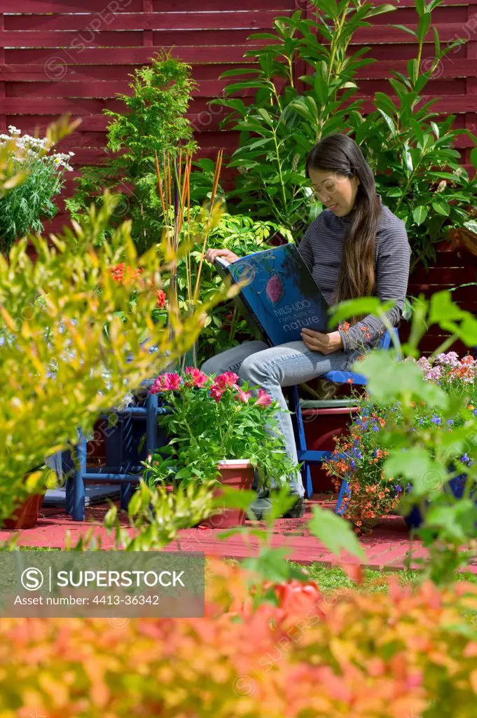 Woman reading on a flowered garden terrace
