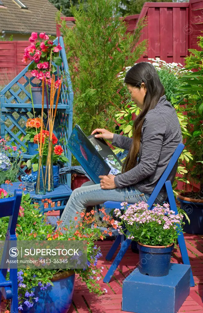 Woman reading on a flowered garden terrace