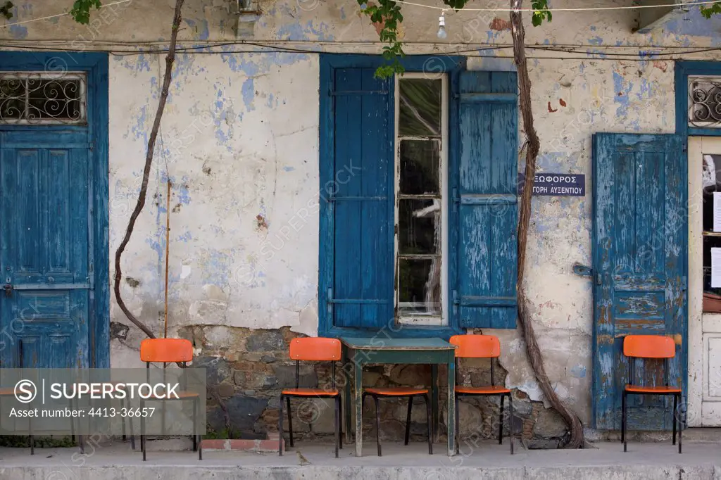Oranges chairs in front of a cafe with blue shutters