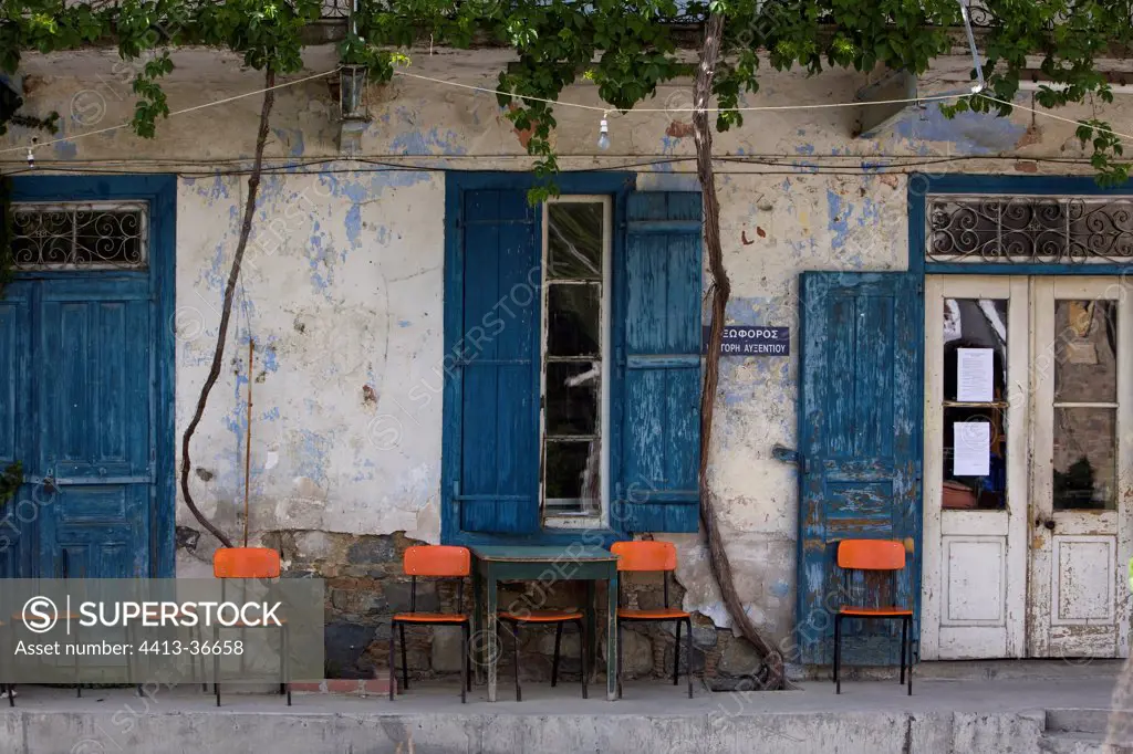 Oranges chairs in front of a cafe with blue shutters